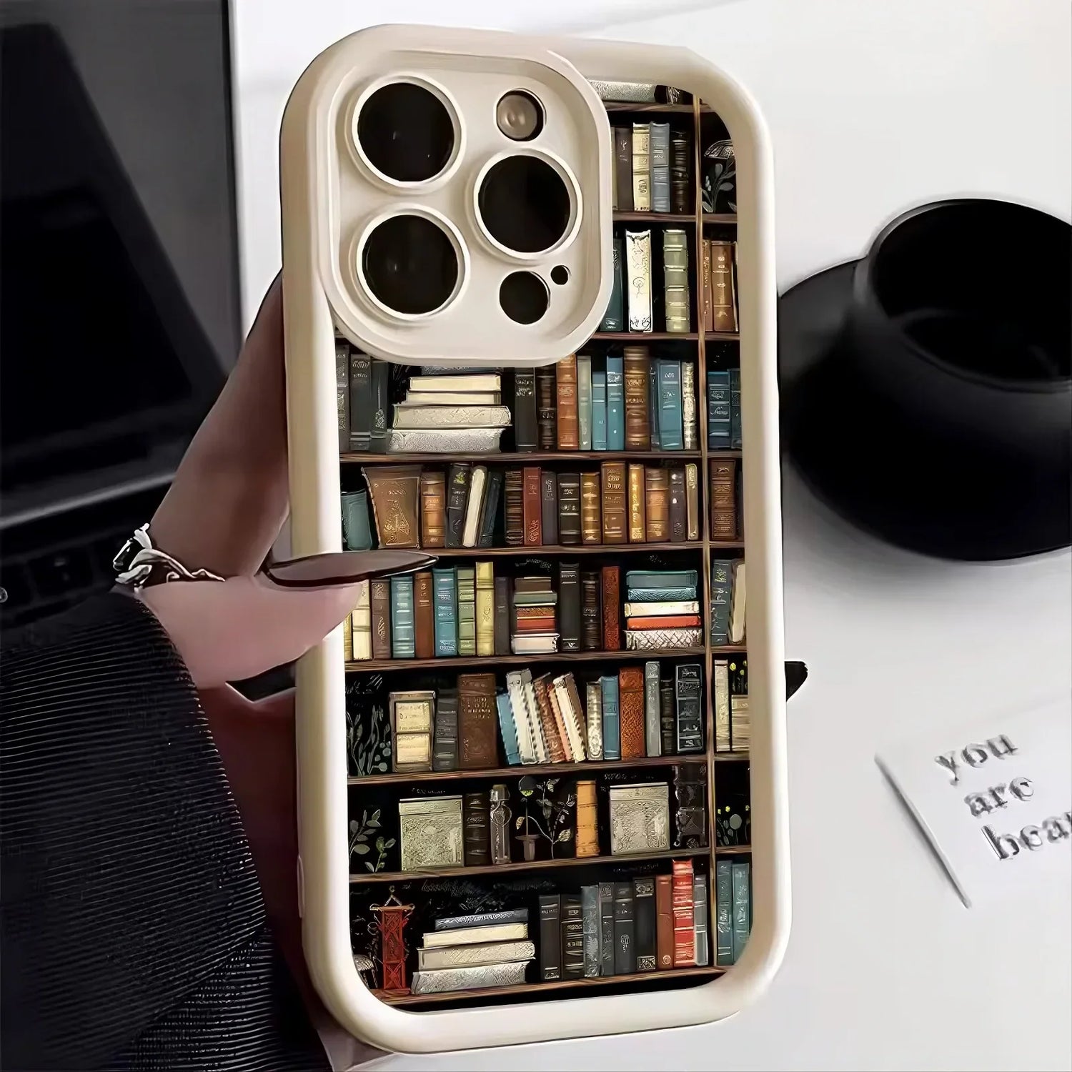 Beige phone case with colorful bookshelf print, hard plastic material, slim fit design