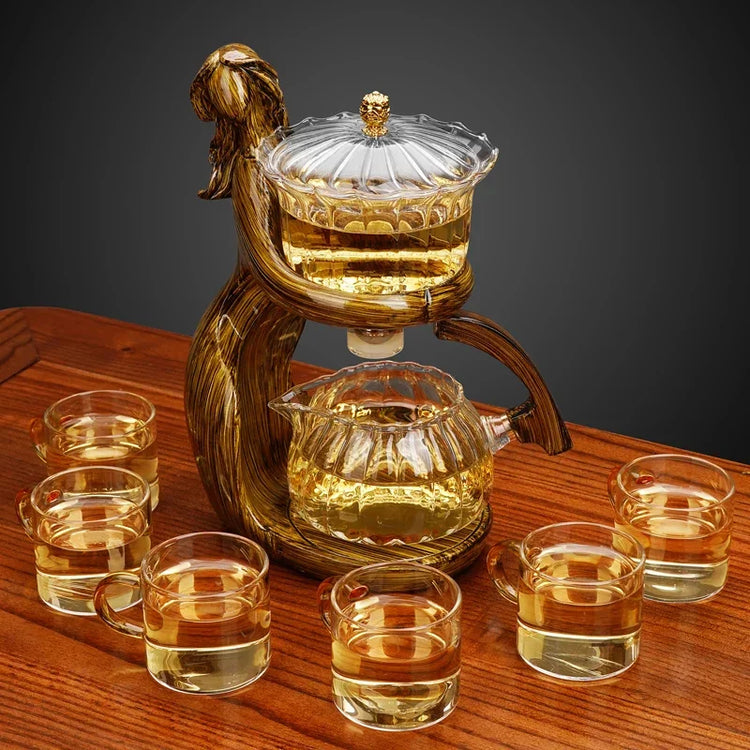 Elegant glass tea set with amber liquid, featuring six cups and a sculpted teapot on wood table.