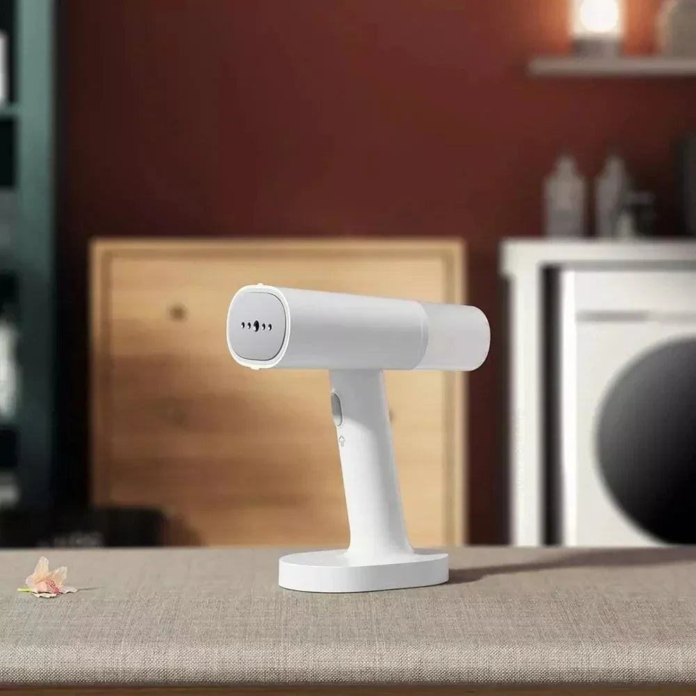 White handheld garment steamer with matte finish on a fabric surface in a modern laundry room