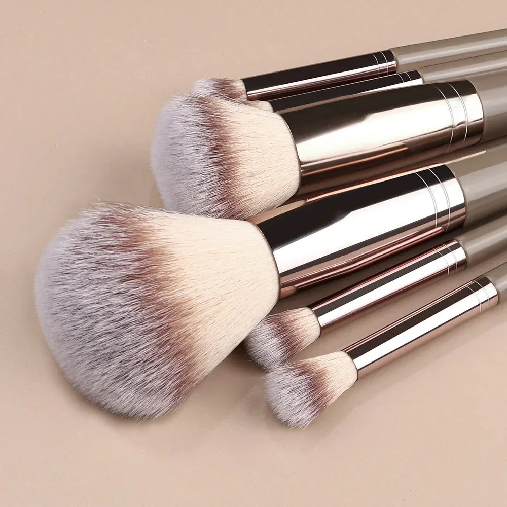 Set of soft synthetic makeup brushes with beige bristles and metallic handles on neutral background