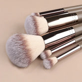 Set of soft synthetic makeup brushes with beige bristles and metallic handles on neutral background