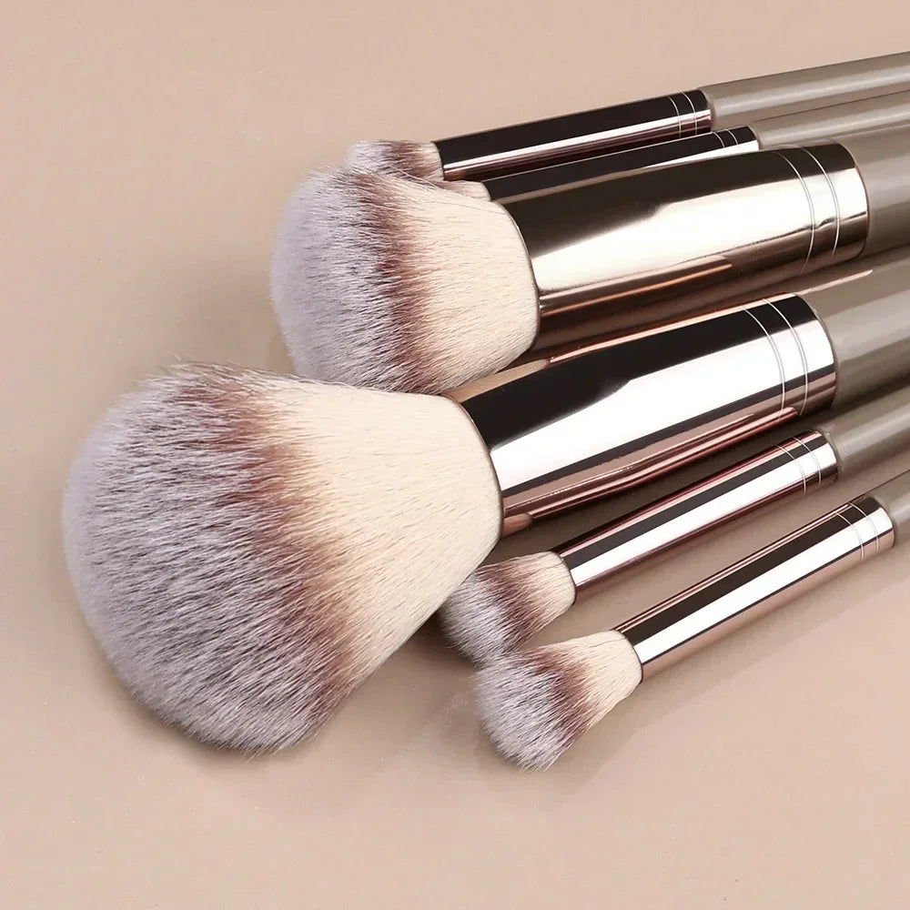 Set of soft synthetic makeup brushes with beige bristles and metallic handles on neutral background