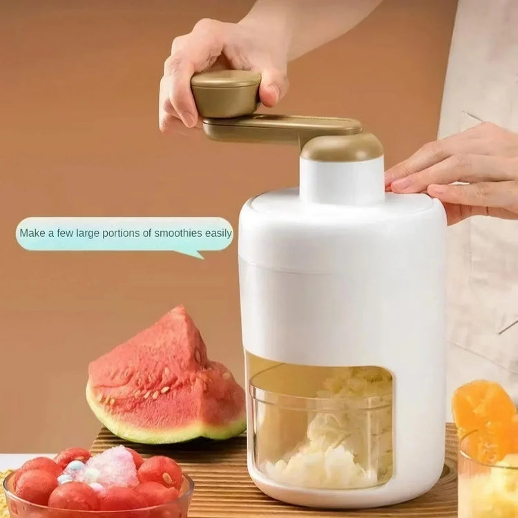 Manual white and gold ice crusher with hand crank, surrounded by fresh fruit on a kitchen table