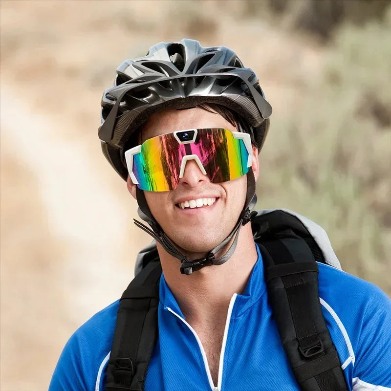 Man in blue zip-up athletic shirt, wearing rainbow mirrored sunglasses and a black bike helmet outdoors