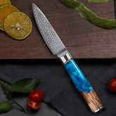 Damascus steel kitchen knife with blue resin and wood handle on cutting board with sliced lime.