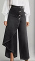 High-waisted black denim wide-leg pants with an asymmetrical draped front panel