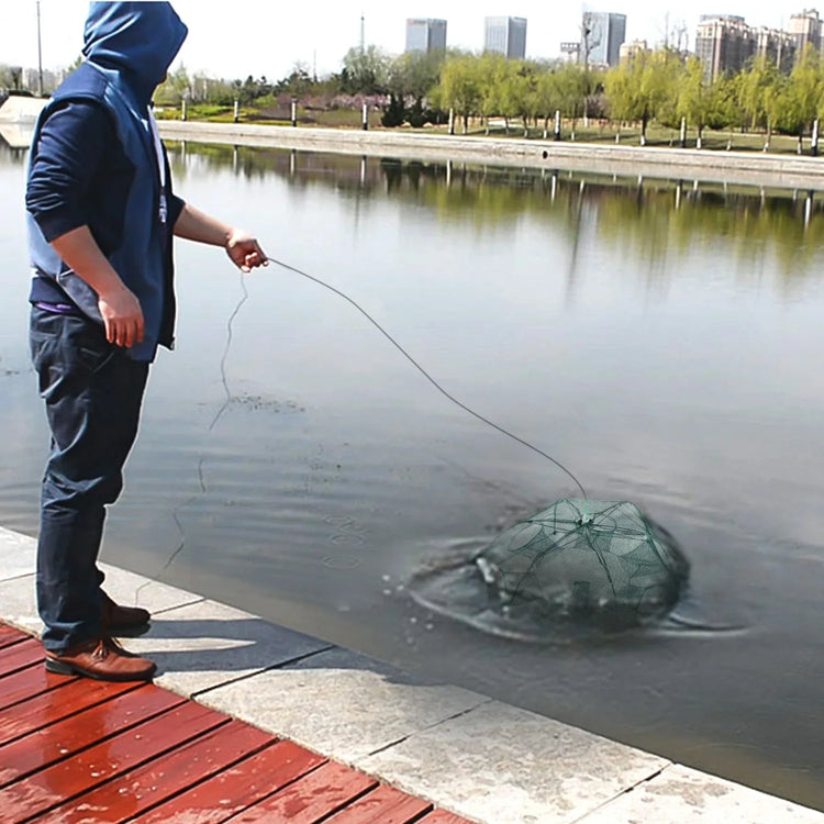 Man in blue hooded jacket and dark pants fishing by a city lake with a collapsible net trap