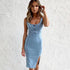 Woman wearing a fitted light blue denim dress with a sleeveless design and side slit