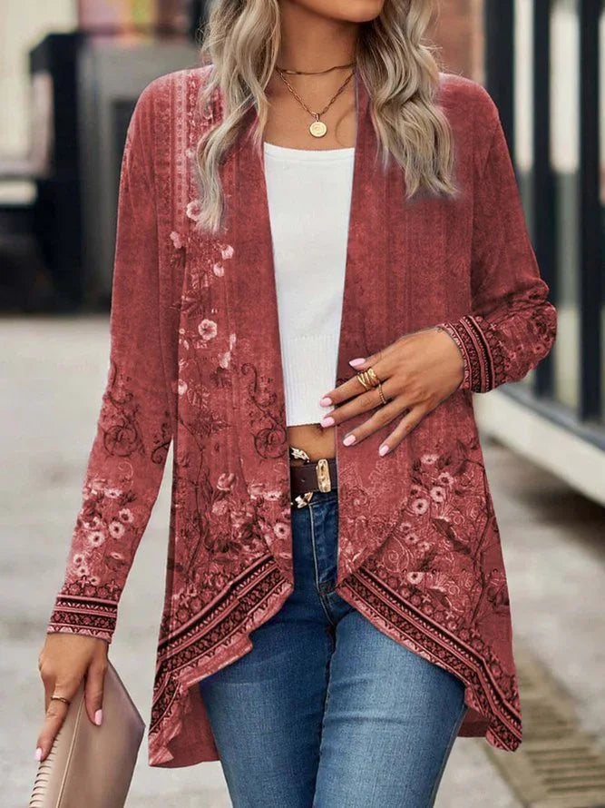 Woman wearing a pink floral long-sleeve open cardigan with asymmetrical hem, white crop top, and blue jeans.