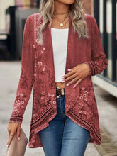 Woman wearing a pink floral long-sleeve open cardigan with asymmetrical hem, white crop top, and blue jeans.