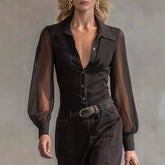 Woman wearing a sheer black long sleeve blouse and high-waisted black pants with a belt