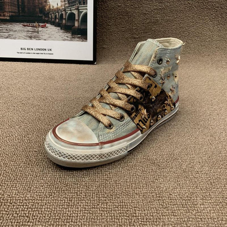 High-top canvas sneaker with gold laces, distressed blue fabric, leopard print, and metal studs.