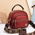 Red faux leather crossbody bag with gold zippers, top handle, and adjustable strap