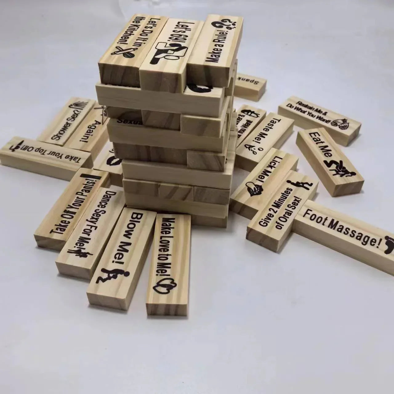 Stack of wooden blocks with playful adult dares and messages engraved on them, arranged for a game.