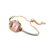 Square gold-tone bracelet watch with pink dial and crystal accents, adjustable chain.