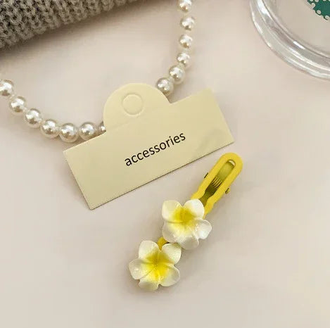 Yellow hair clip with white and yellow flower accents, pearl necklace accessory