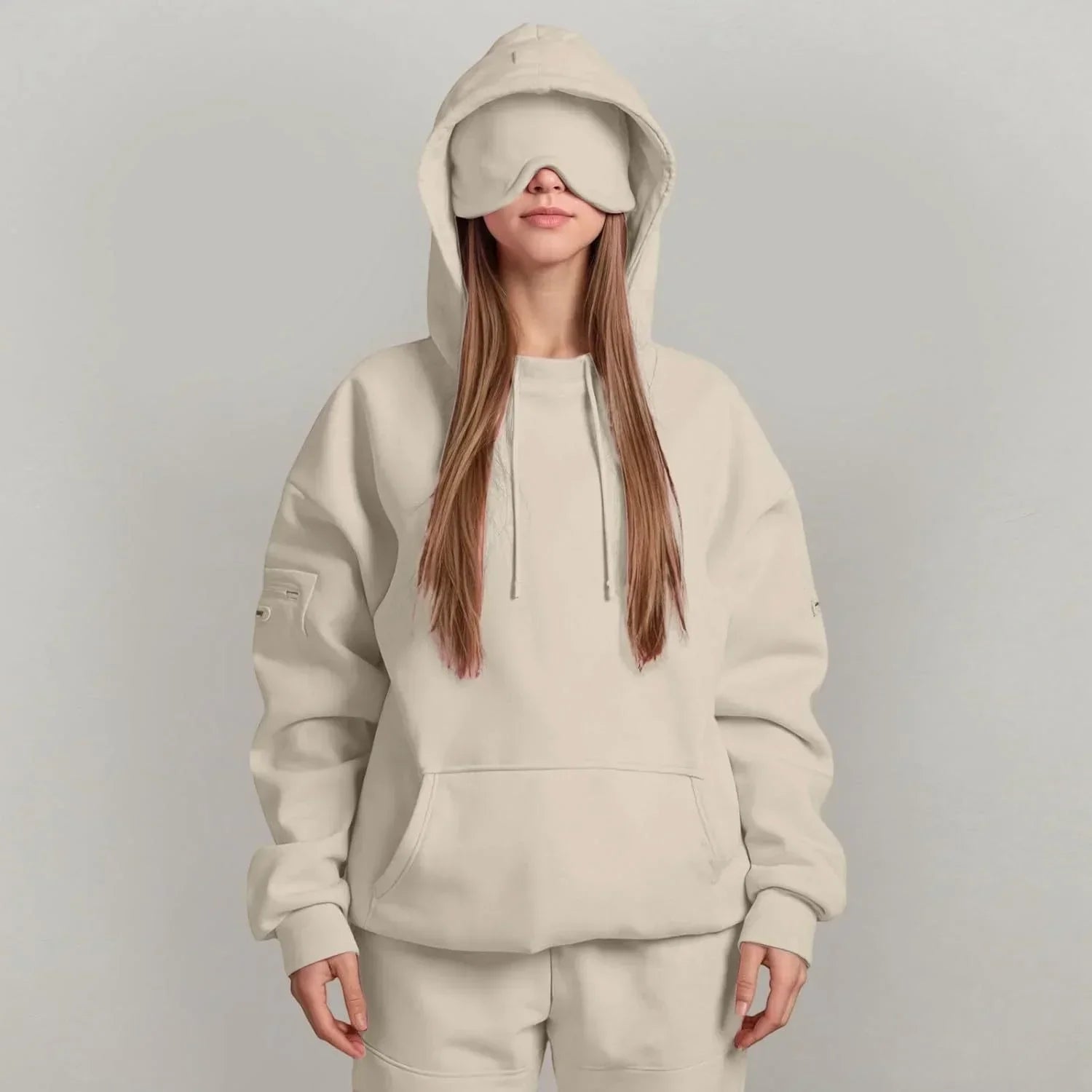Woman in oversized beige hoodie and sweatpants with relaxed fit and matching eye mask