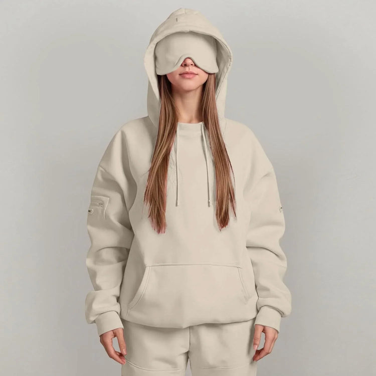 Woman in oversized beige hoodie and sweatpants with relaxed fit and matching eye mask