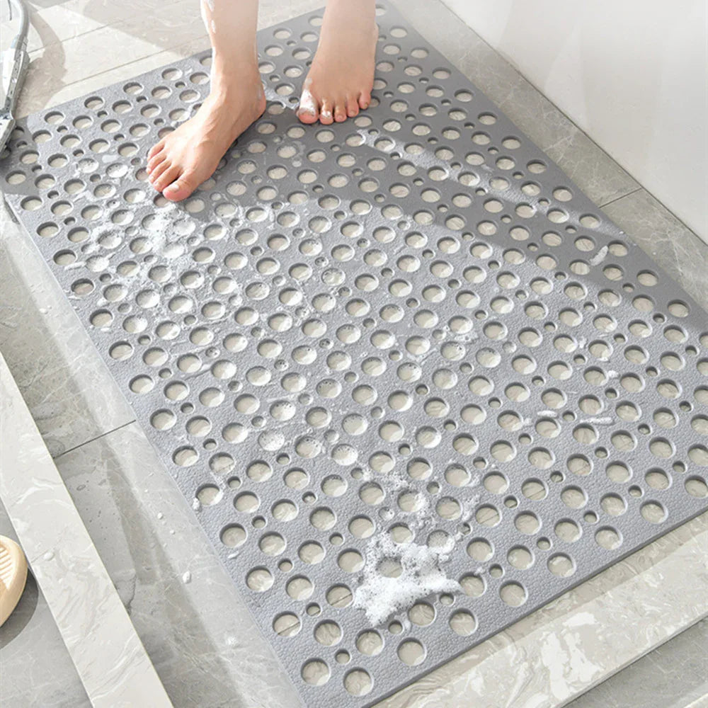 Gray non-slip shower mat with drainage holes, textured rubber material, in use on bathroom floor