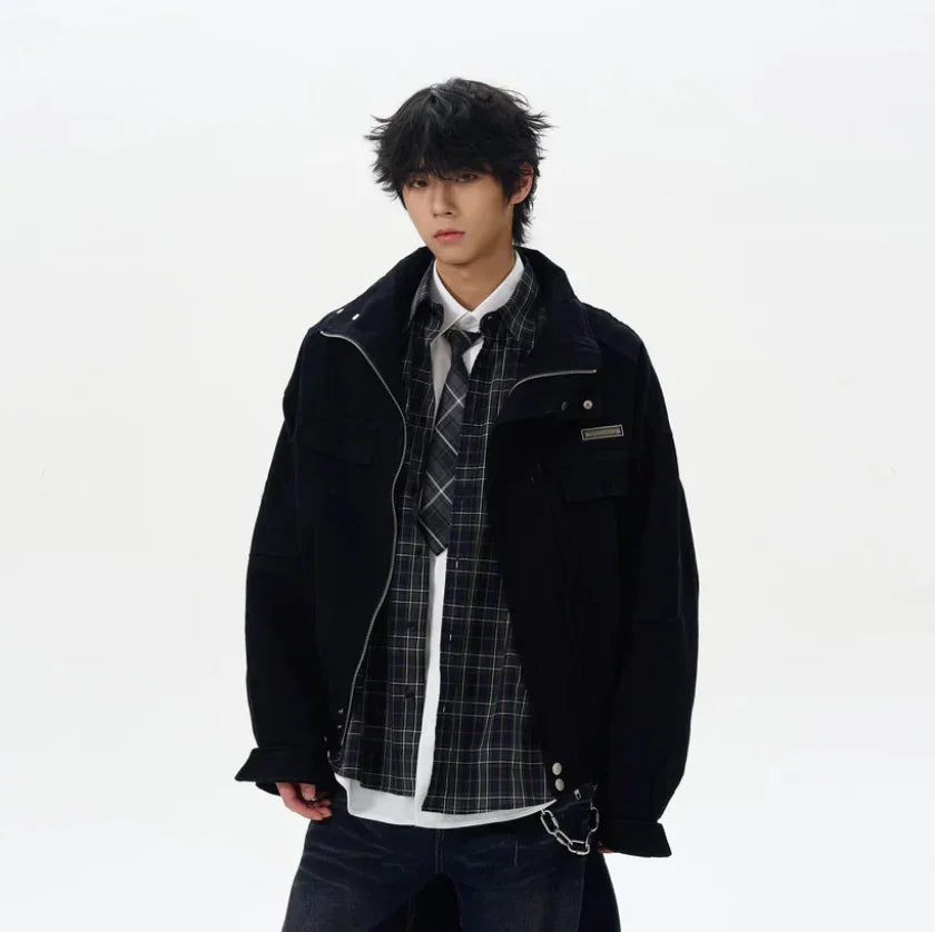 Man wearing oversized black jacket, plaid shirt, tie, and dark jeans, streetwear style