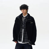 Man wearing oversized black jacket, plaid shirt, tie, and dark jeans, streetwear style