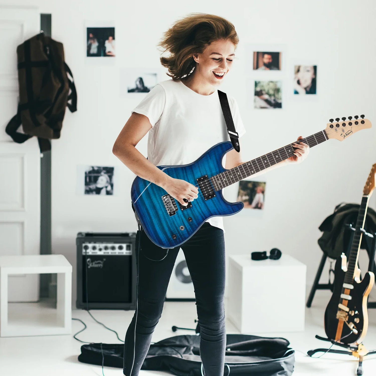 Woman wearing a white cotton t-shirt and slim black jeans, playing guitar in a modern room