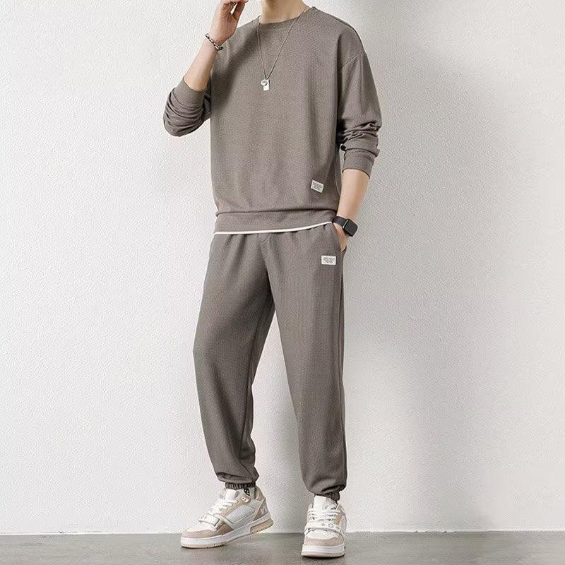 Man wearing relaxed fit taupe streetwear sweatshirt and jogger pants set with sneakers
