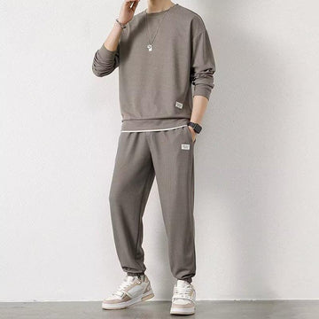 Man wearing relaxed fit taupe streetwear sweatshirt and jogger pants set with sneakers