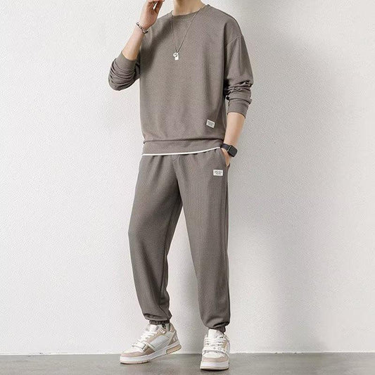 Man wearing relaxed fit taupe streetwear sweatshirt and jogger pants set with sneakers