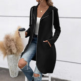 Woman wearing a black long hoodie coat, white tank top, ripped blue jeans, casual streetwear style.