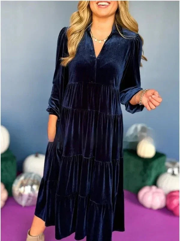Woman wearing a loose fit, navy blue velvet midi dress with tiered skirt and long sleeves