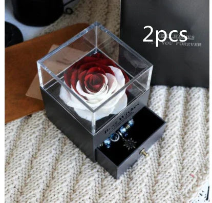 Red and white preserved rose in clear display box with jewelry drawer, on knitted surface