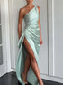 Woman wearing a light green satin one-shoulder gown with high slit and elegant draping