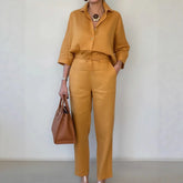 Woman wearing loose-fit mustard yellow shirt and matching straight-leg pants, carrying brown tote bag
