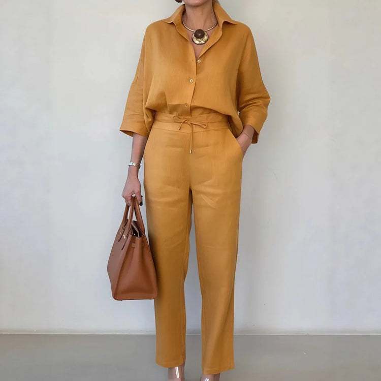 Woman wearing loose-fit mustard yellow shirt and matching straight-leg pants, carrying brown tote bag