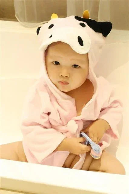 Baby in soft pink bathrobe with cow hood, sitting in bathtub, plush animal loungewear