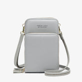 Light grey faux leather crossbody bag with adjustable strap and zip closure, minimalist design