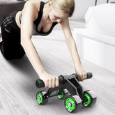 Woman in a black sporty crop top and leggings using a four-wheel ab roller on wood floor