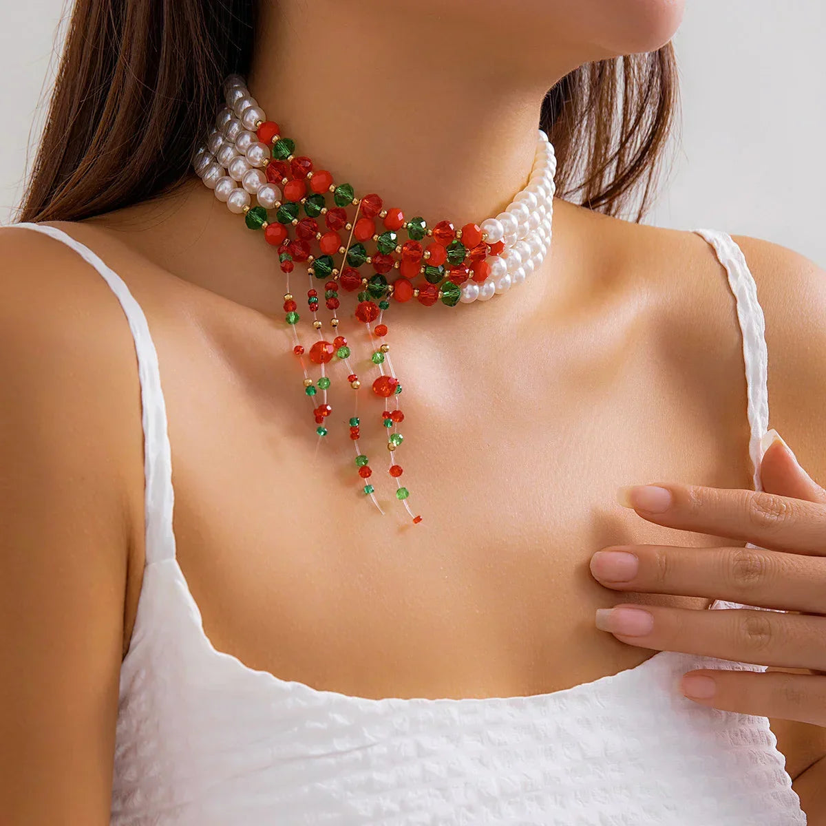 Woman wearing a white textured sleeveless top with a layered pearl and beaded choker necklace