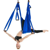 Woman in black sports bra and leggings performing aerial yoga with blue swing hammock