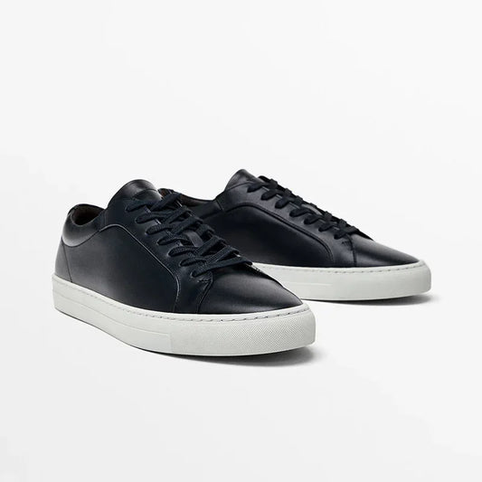 Black leather low-top sneakers with white rubber soles and lace-up closure, minimalist style