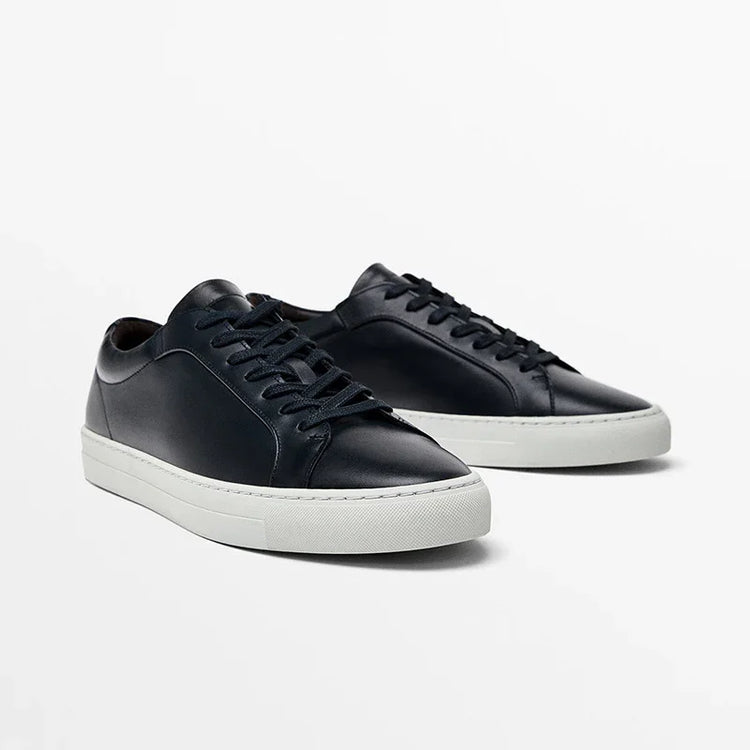 Black leather low-top sneakers with white rubber soles and lace-up closure, minimalist style