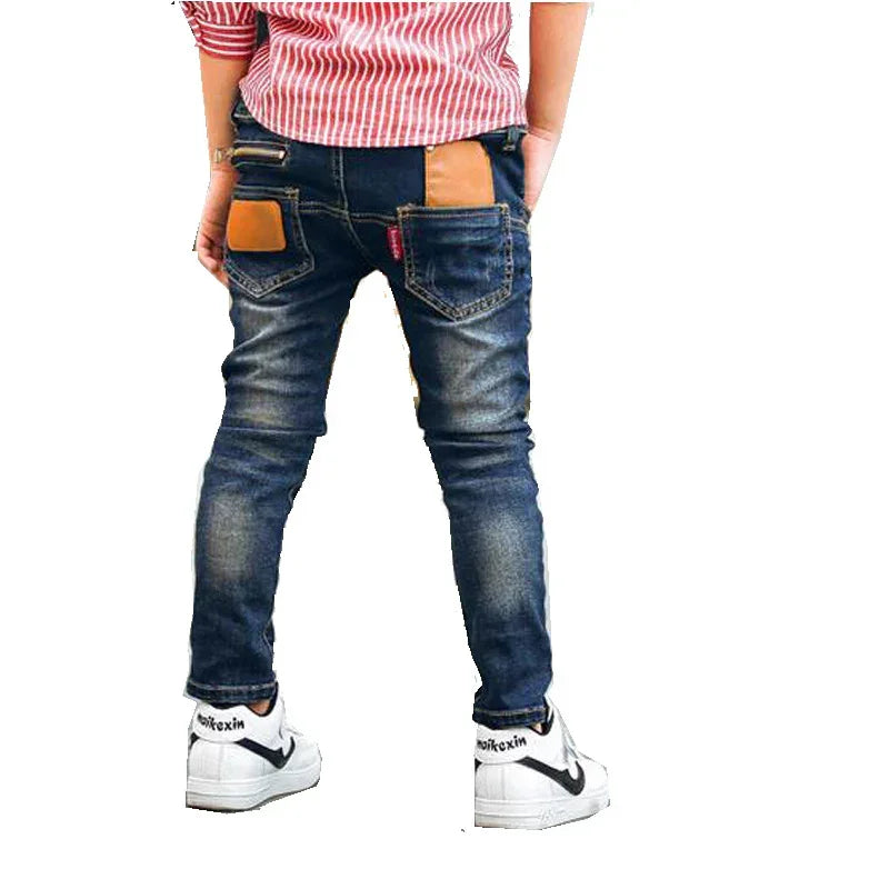 Boy wearing slim fit blue denim jeans with tan patchwork and casual sneakers