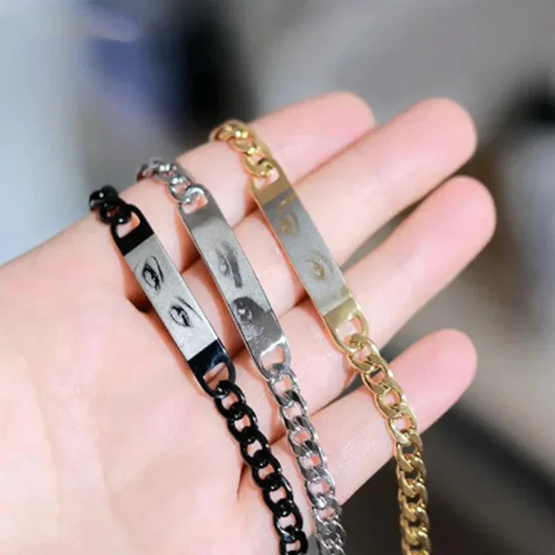 Close-up of three chain bracelets in black, silver, and gold with engraved eyes design.