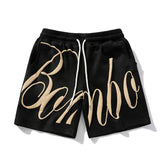 Black streetwear shorts with beige graffiti script, elastic waistband, and relaxed fit