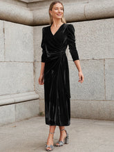 Woman in black velvet wrap dress with long sleeves and gathered waist, midi length