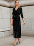 Woman in black velvet wrap dress with long sleeves and gathered waist, midi length