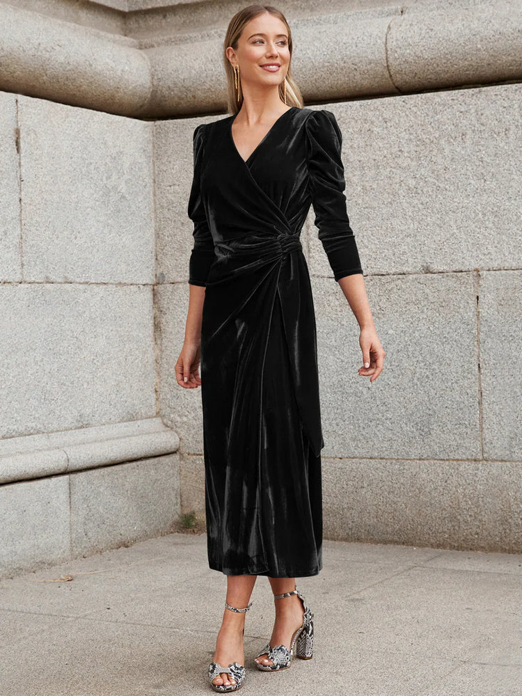 Woman in black velvet wrap dress with long sleeves and gathered waist, midi length