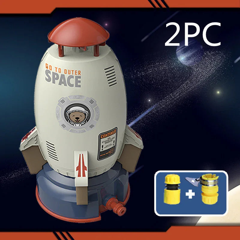 Rocket-shaped water sprinkler toy in gray and red plastic with space-themed design and hose connectors.