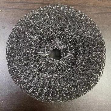Black mesh circular scrubber, metallic texture, close-knit spiral design, on dark surface.